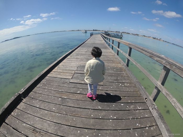 Rear view full length of girl amidst sea on pier
