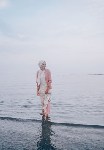 Woman standing on sea against sky