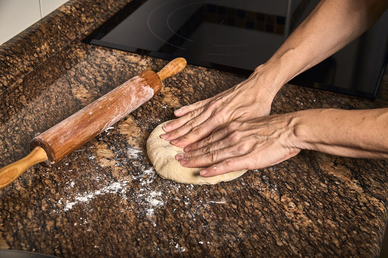 Woman hands working on a dough to cook a tasty pizza