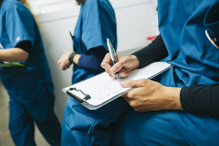 Male nurse writing medical report while sitting in veterinary clinic