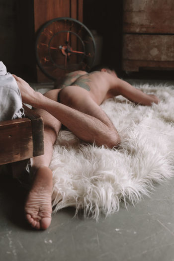 Rear view of naked man lying down on fur