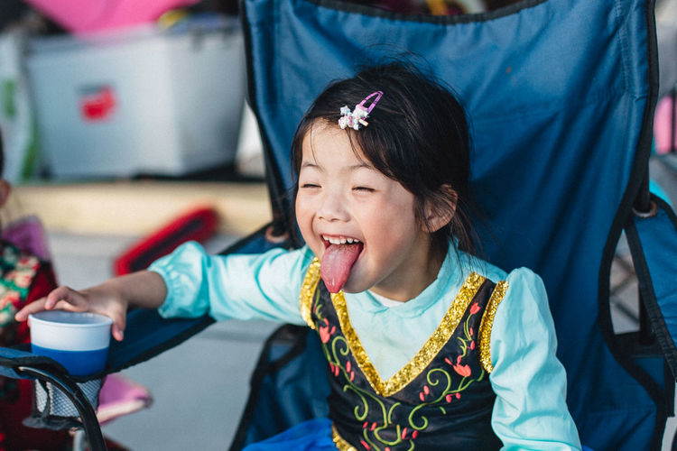 Girl sticking out tongue while sitting on chair