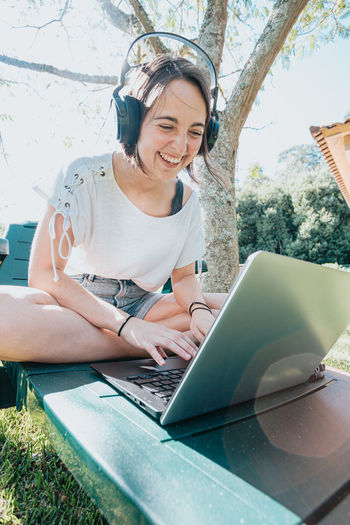 Happy woman using laptop in park