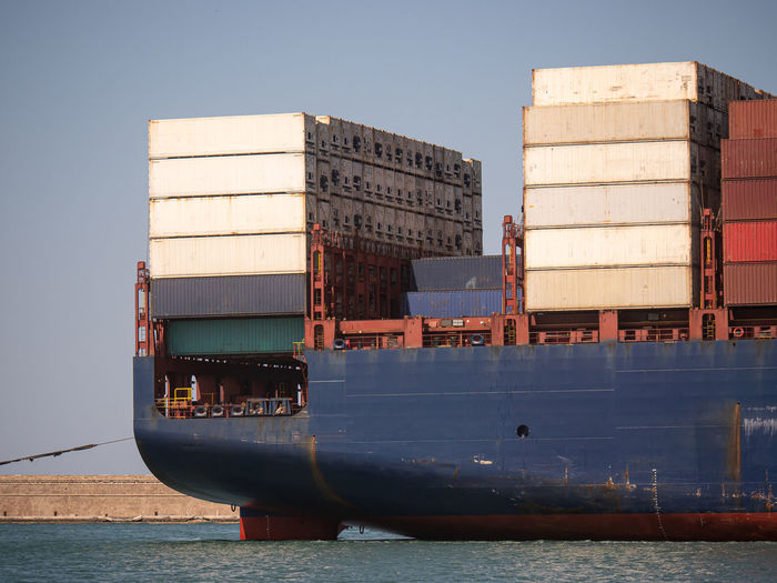Detail of the stern of a large blue container ship loaded with goods.
