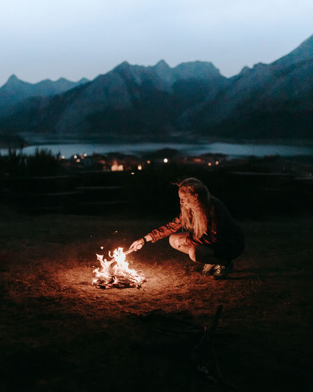 High angle view of hiker making a campfire by lake against mountain range