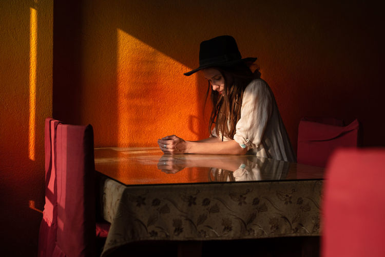 Portrait of young woman in hat sit alone in cafe