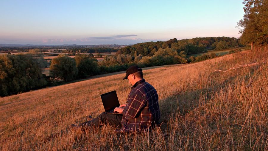 Man using laptop sitting on a hill