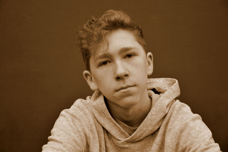 Portrait of teenage boy against brown background