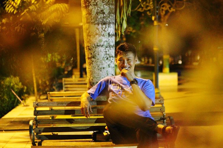 Portrait of man sitting at park at night