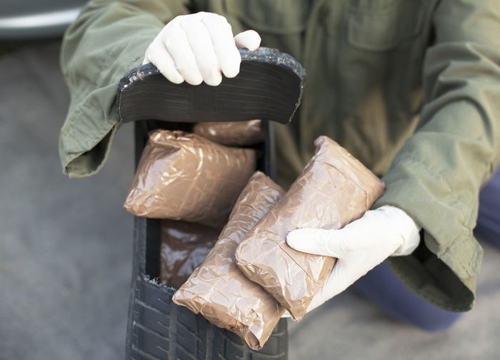 Low section of man holding cocaine parcels