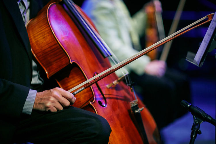 Midsection of musician playing cello on stage