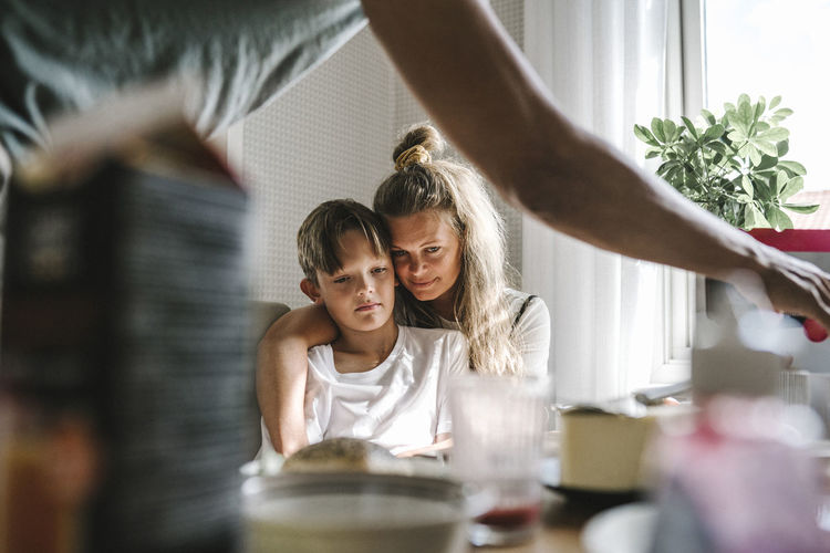 Mother embracing tired son at home