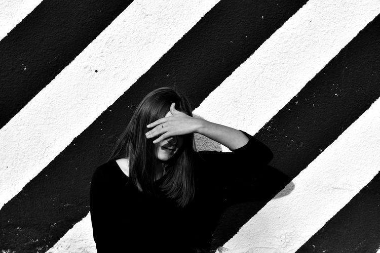 Young woman standing against geometric wall black and white 