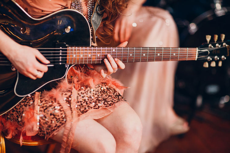 Midsection of woman playing guitar