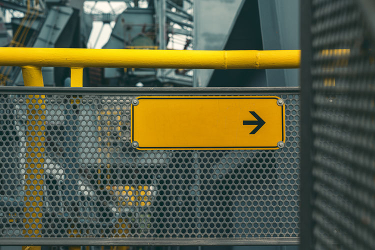 Close-up of yellow sign on metal fence