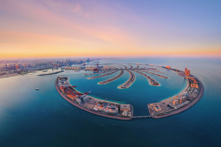 Aerial view of cityscape and sea against sky during sunset
