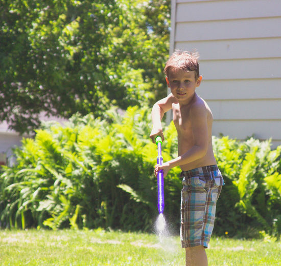 Full length of shirtless boy playing with water