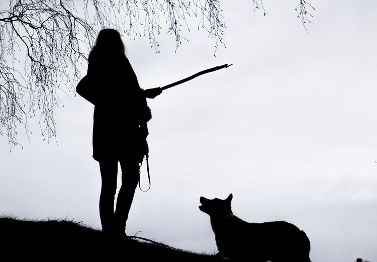 Silhouette of woman with pet dog against clear sky