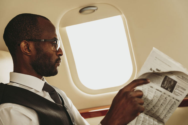 Young businessman concentrating while reading newspaper in private jet