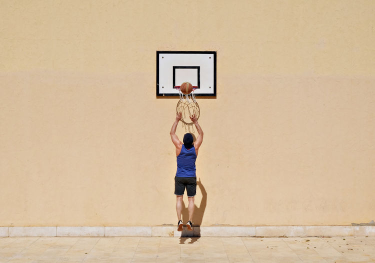 Full length of man jumping at basketball hoop