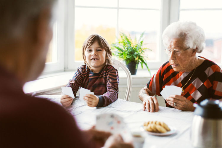 Happy boy playing cards with great grandparents at home