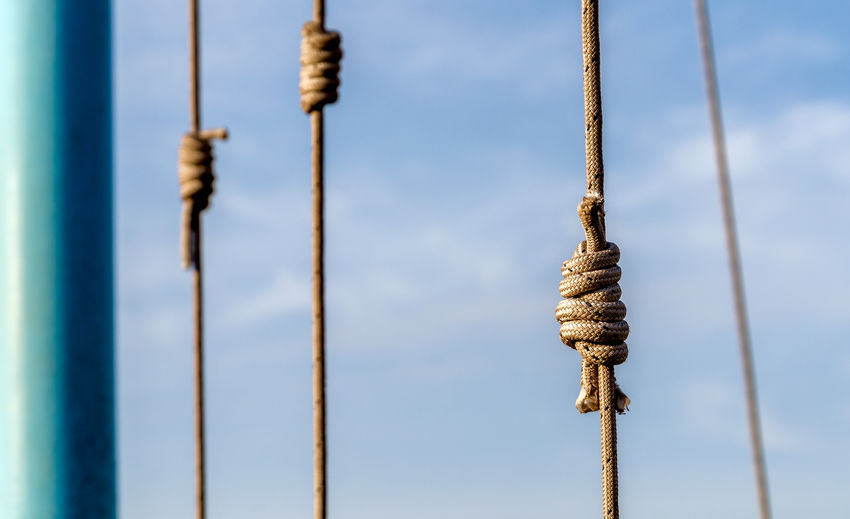 Low angle view of rope tied on wooden post