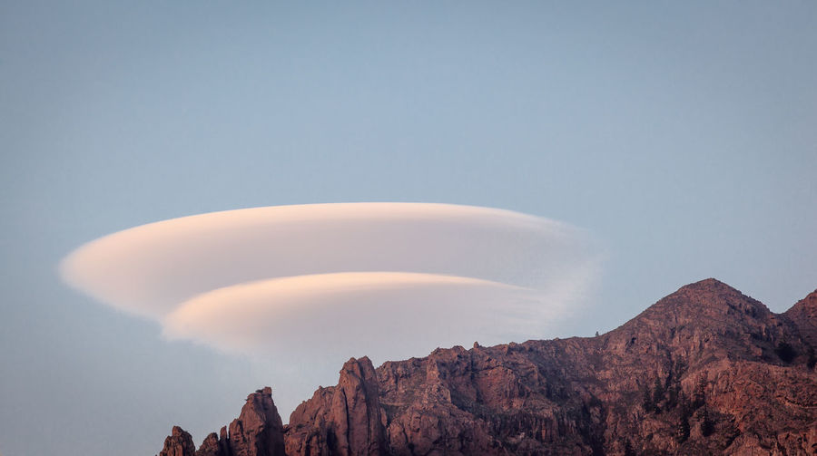 Lenticular  clouds in classic doughnut shape over a mountain ridge. 