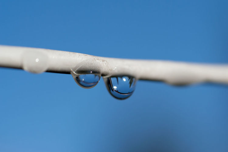 Close-up of water drop against clear blue sky
