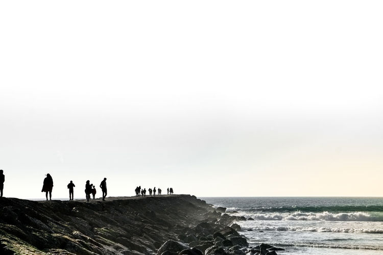 People on beach against clear sky