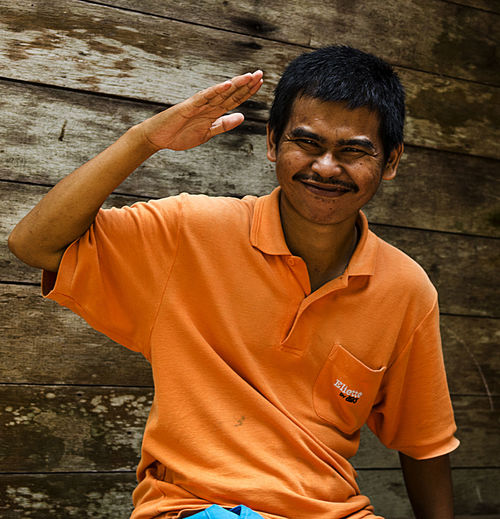 Portrait of smiling man saluting against wall