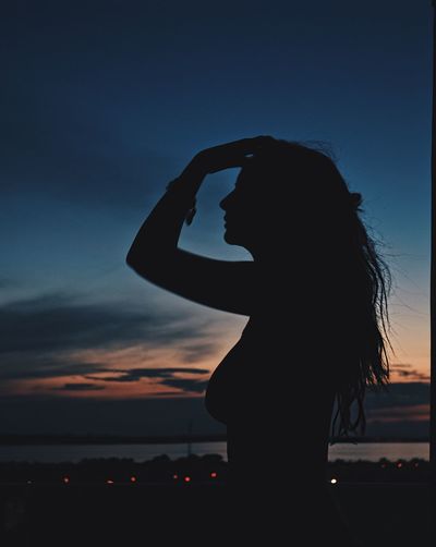 Silhouette woman standing by sea against sky during sunset
