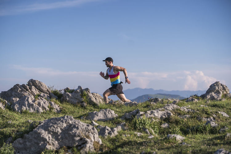 Sportsman running on mountain against clear sky