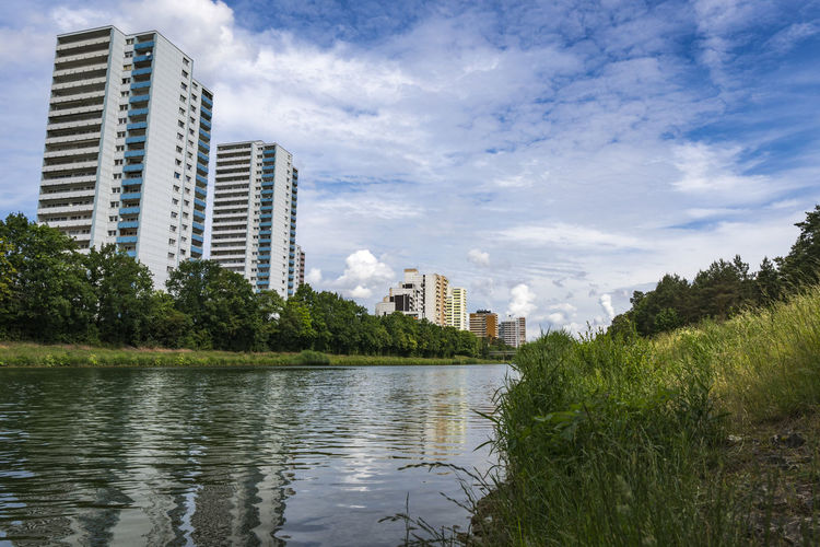 Buildings by river against sky in city