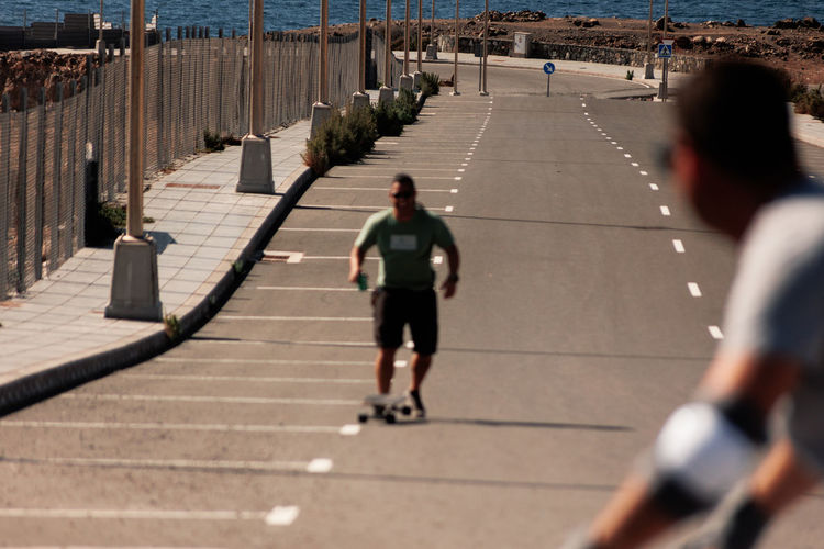 A man playing figure skating on a rural road in the sun on a bright day,play surf skate