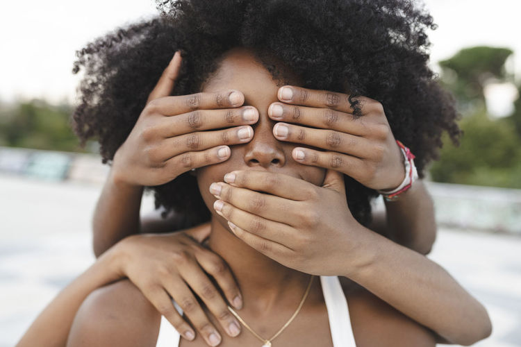 Close-up portrait of woman covering face with hands