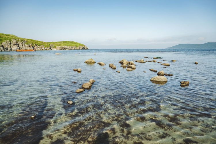 Summer sea panorama. shallow, clear, transparent sea with reefs, rocks and green hills around