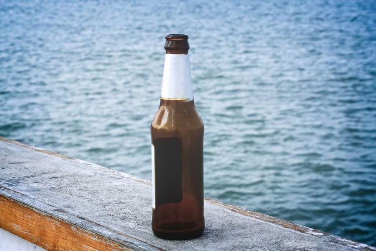 Empty bottle of beer on the bridge by the sea