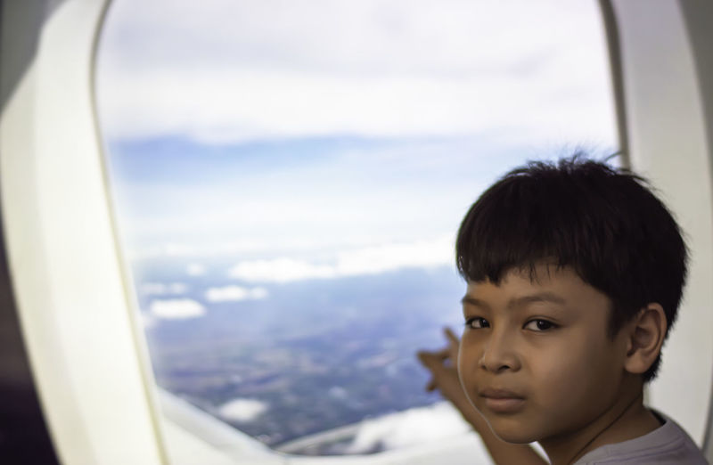 Portrait of boy looking through airplane window