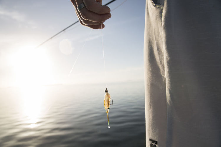 A close up of a fisherman holding fishing line with dripping lure