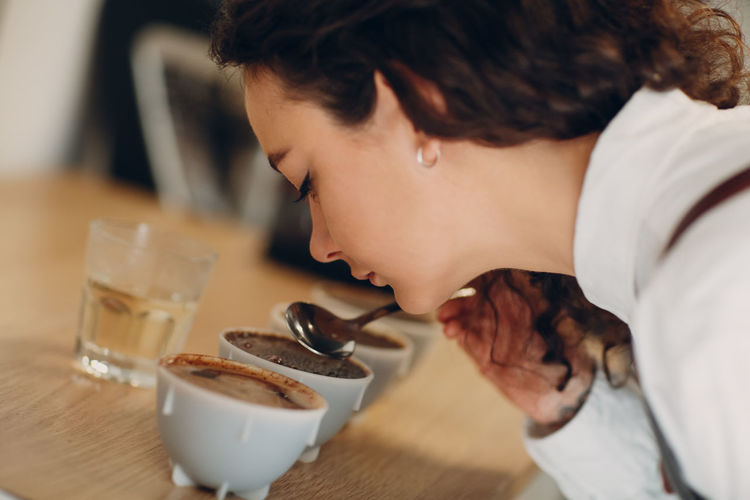Woman smelling coffee on table