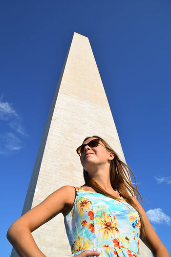 Low angle view of woman standing by washington monument against sky