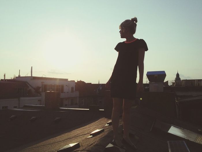 Full length of young woman standing on roof