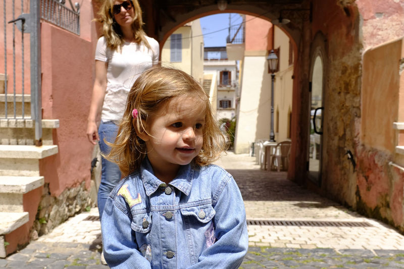Girl with mother in background standing on footpath