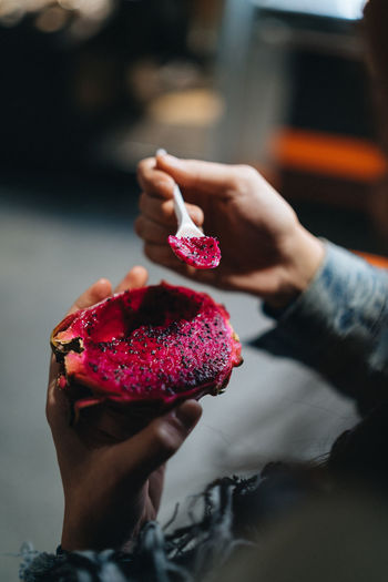 Cropped hand of woman eating pitaya at home