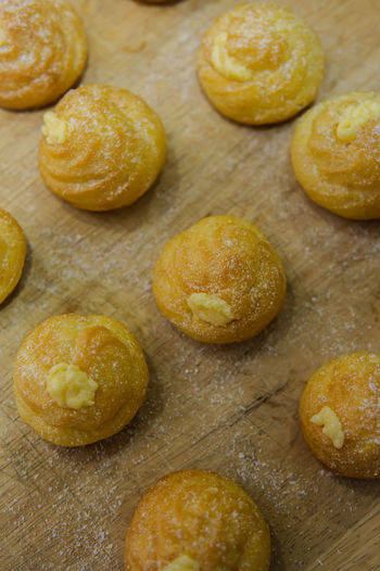 Mini cream puff or profiterole with dusting powdered sugar on a wooden background. pastry ball.