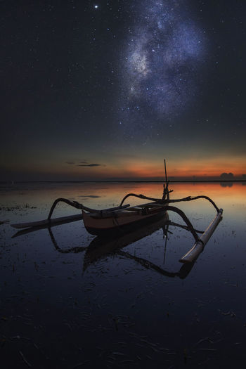 Boat in lake against sky at night