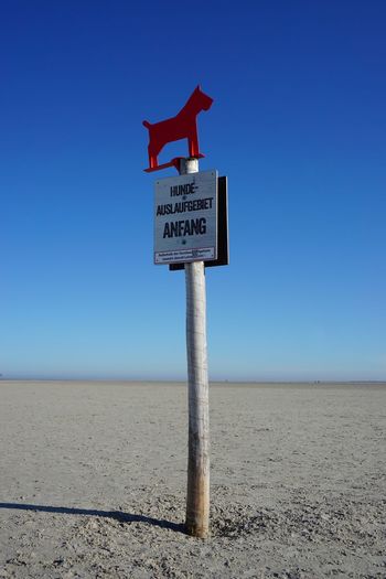 Information sign on beach against clear blue sky
