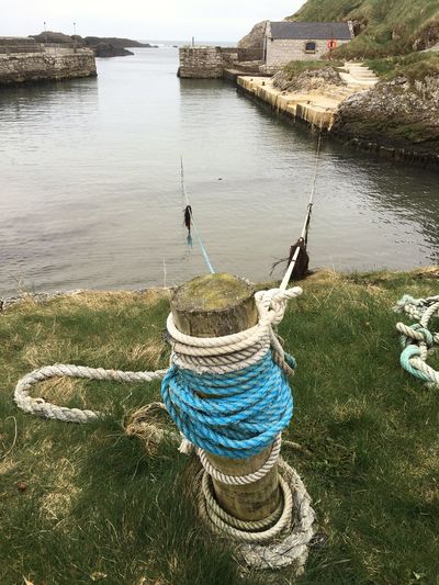 Wooden post with rope on harbor at ballintoy