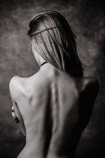 Rear view of shirtless woman standing outdoors