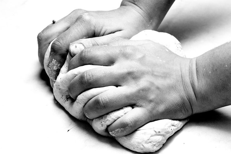 Cropped hands of woman kneading dough on table